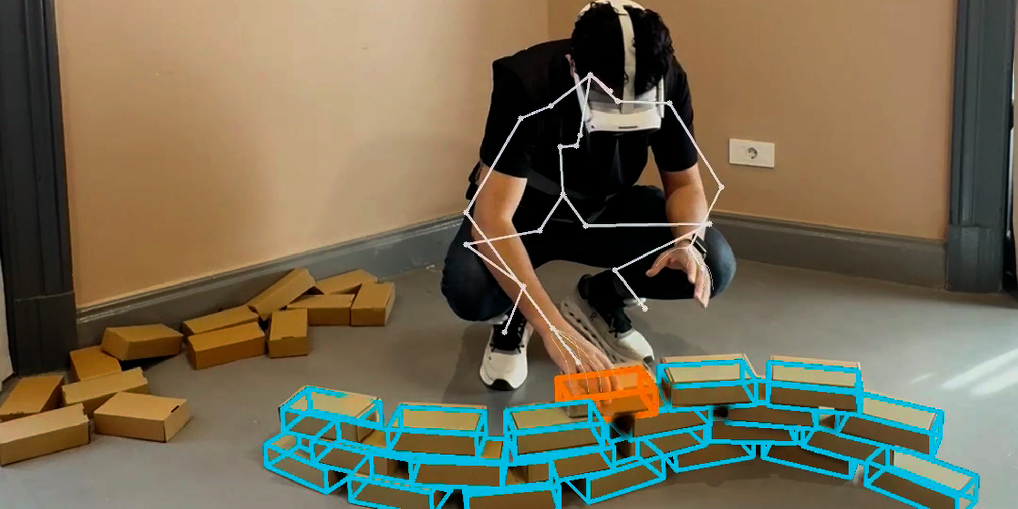 A demonstrator crouched mid-task with their recorded whole-body skeleton drawn over them, laying a brick wall against the cyan design specification registered into the workspace, the component currently being placed highlighted in orange.